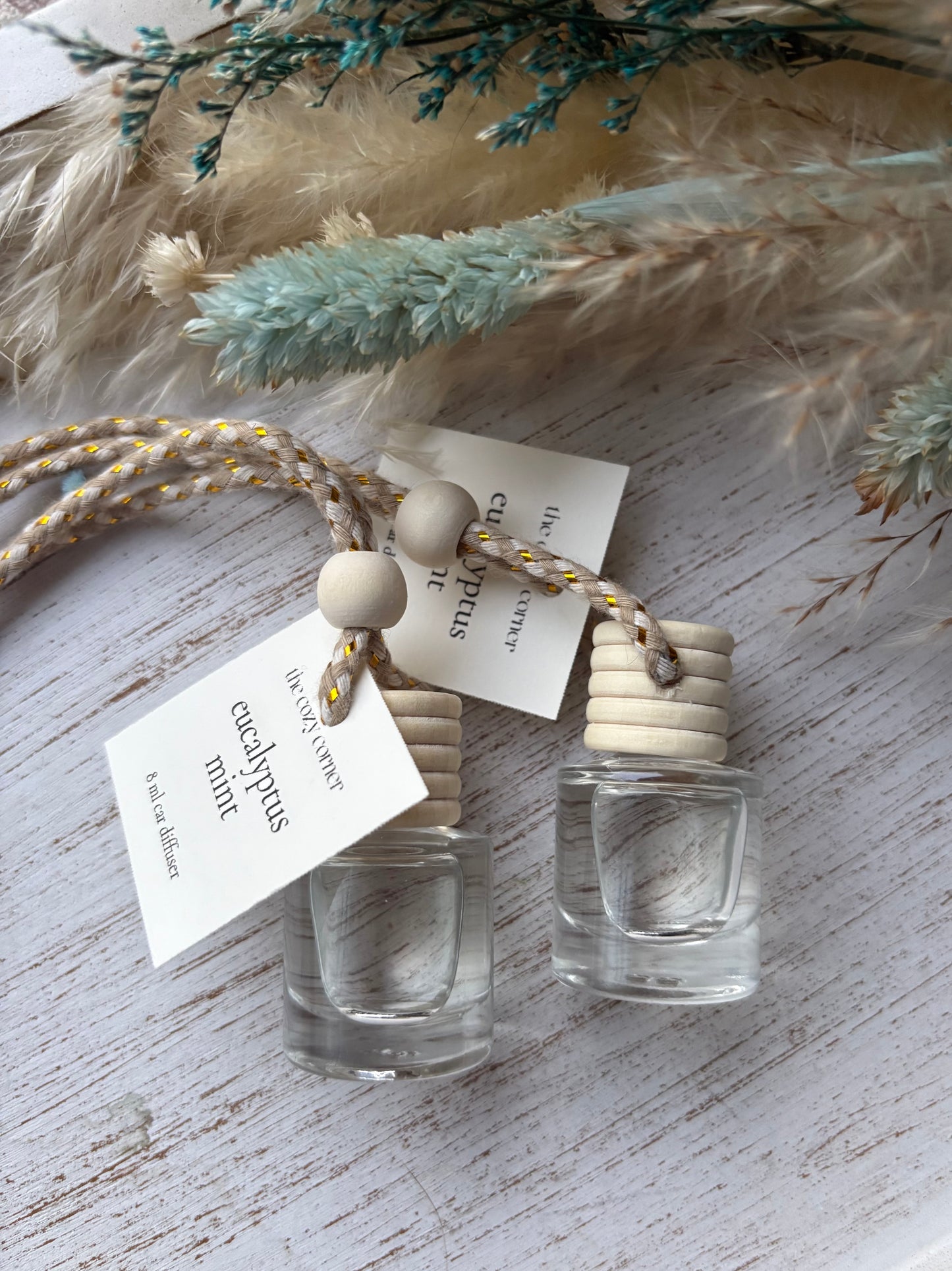 Two small glass bottles with wooden caps on a textured surface with decorative elements.