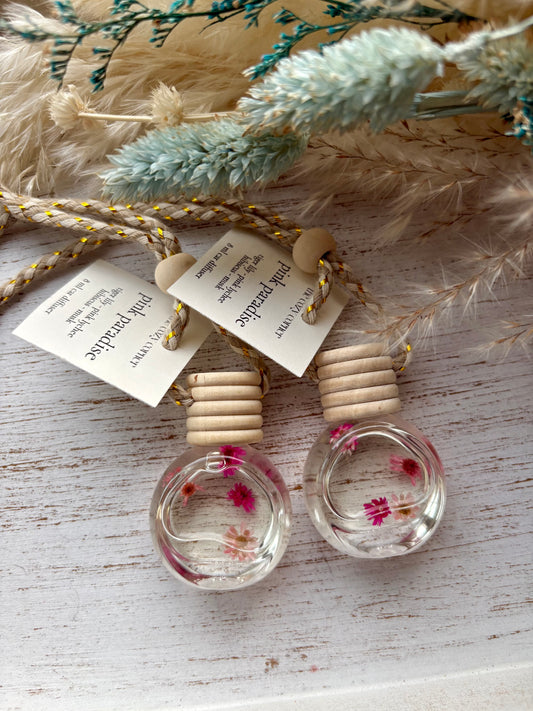 Two small glass containers with floral elements on a wooden surface with decorative elements.