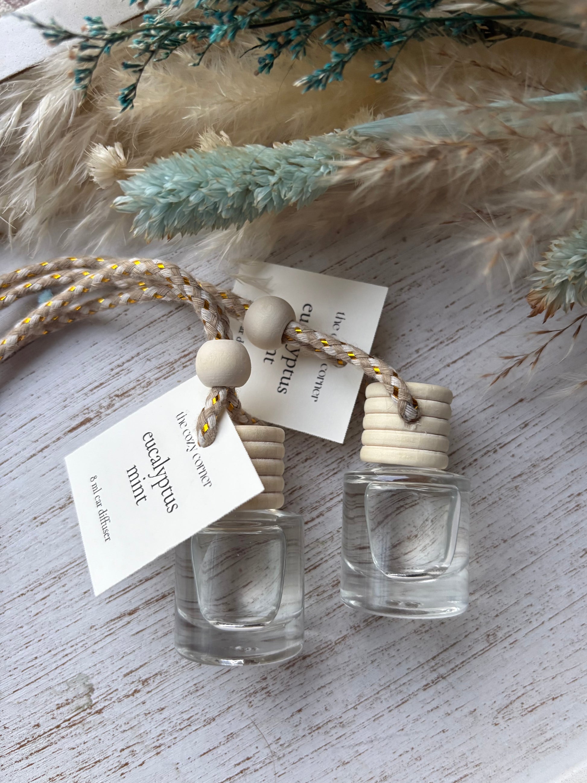 Two small glass bottles with wooden caps on a textured surface with decorative elements.