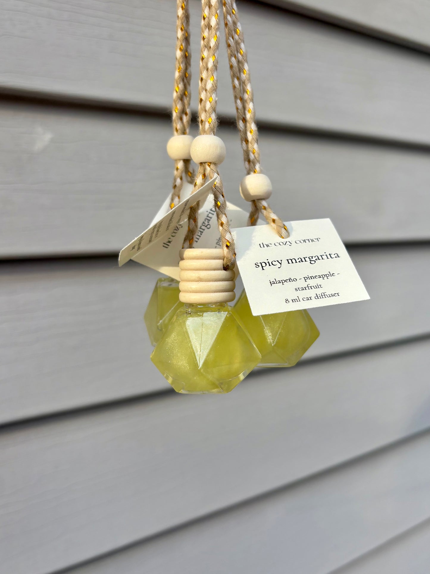 Decorative oil diffuser with geometric design and wooden beads on a gray background