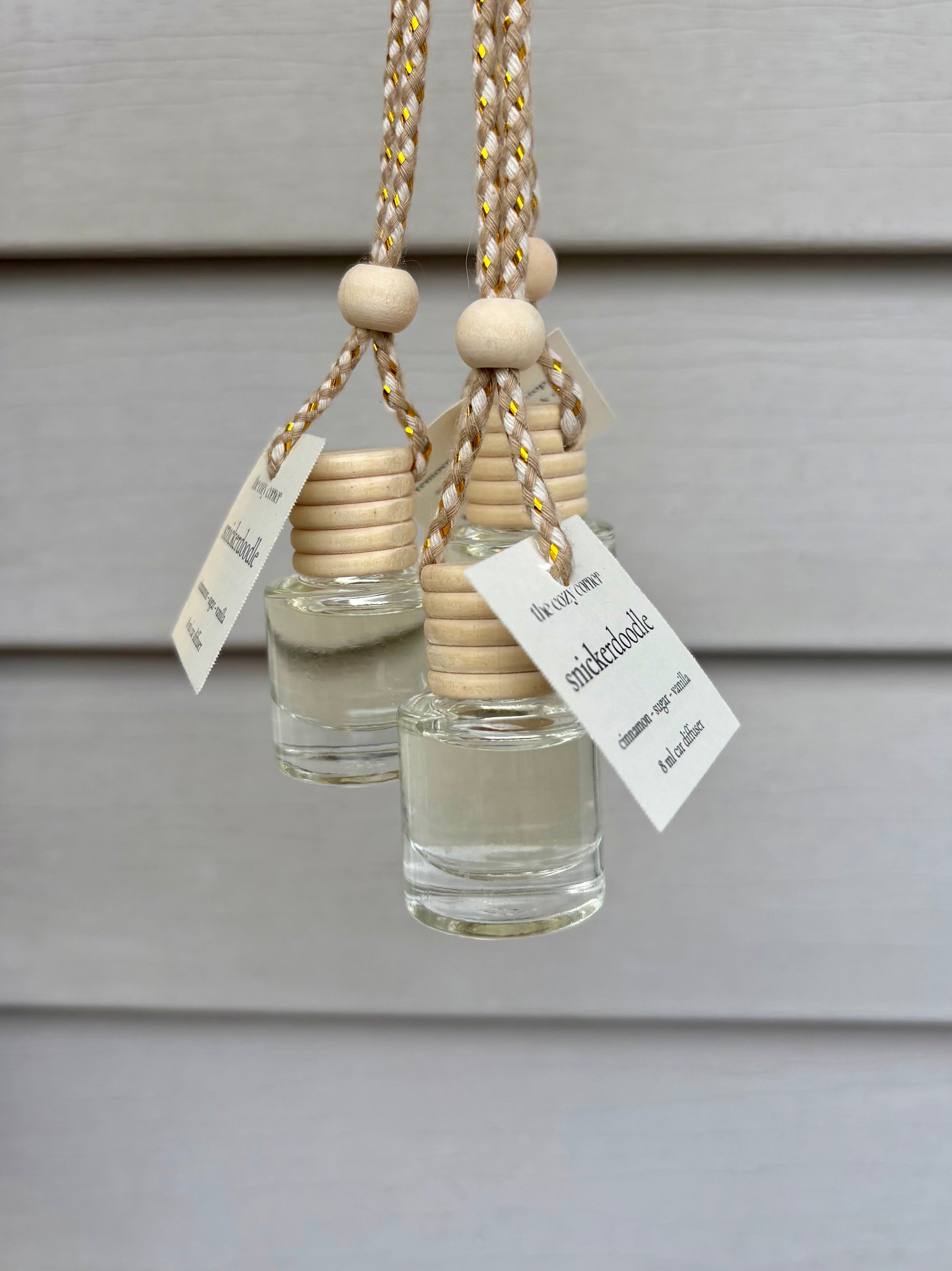 Two small glass bottles with wooden beads and labels on a neutral background
