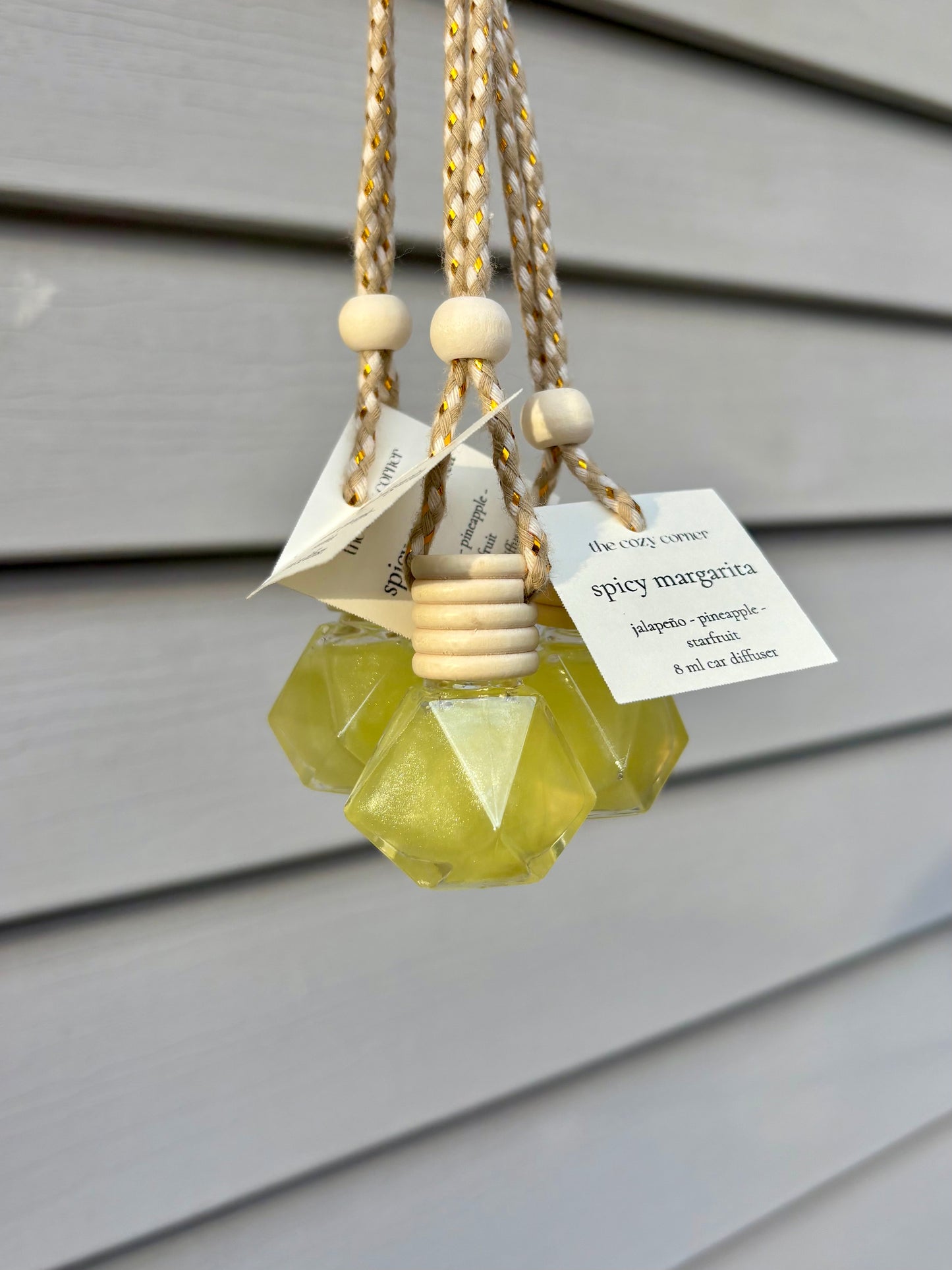 Decorative hanging diffuser with geometric design and wooden beads on a neutral background