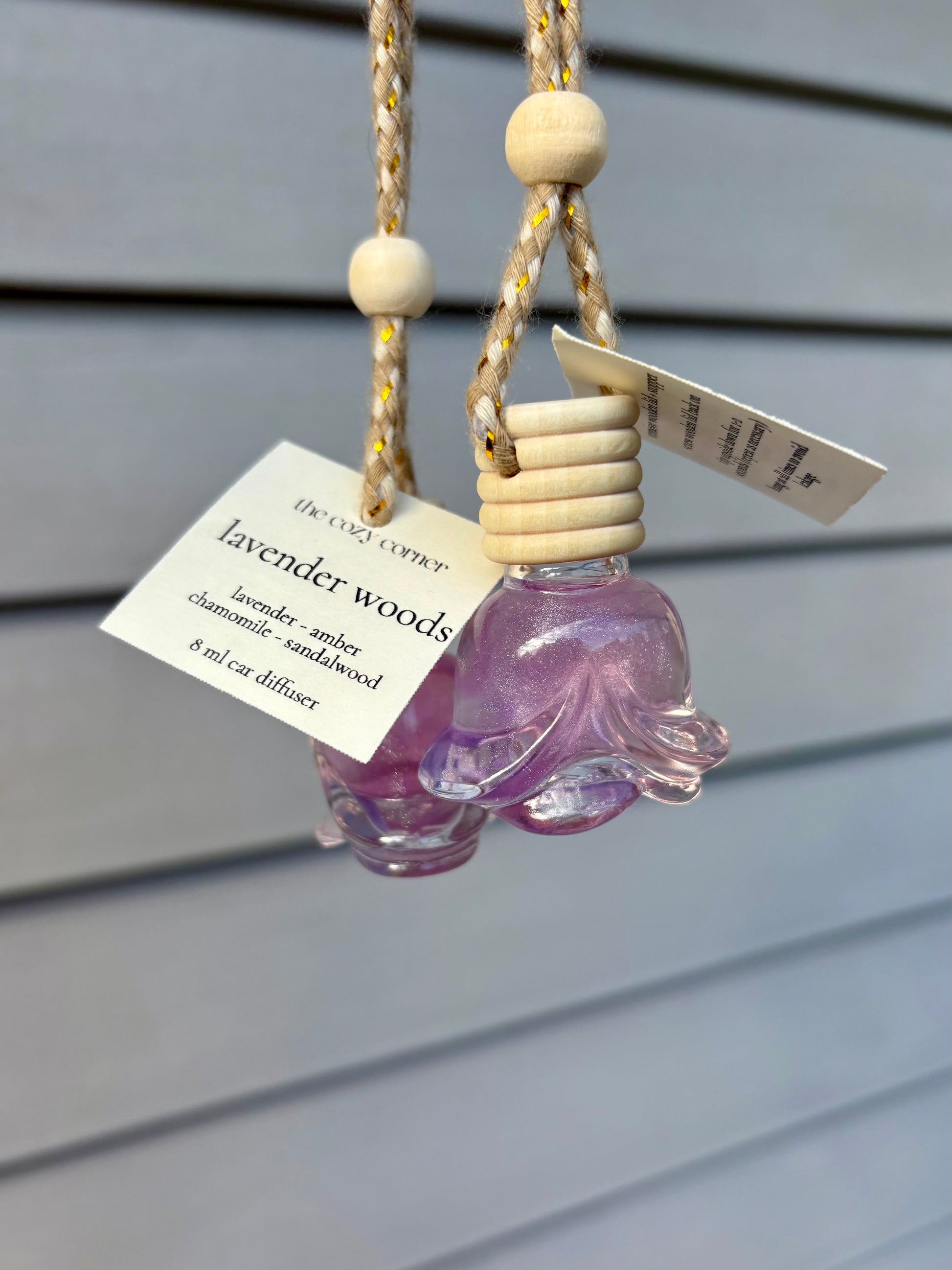 Purple bottle with wooden beads and a tag on a gray background