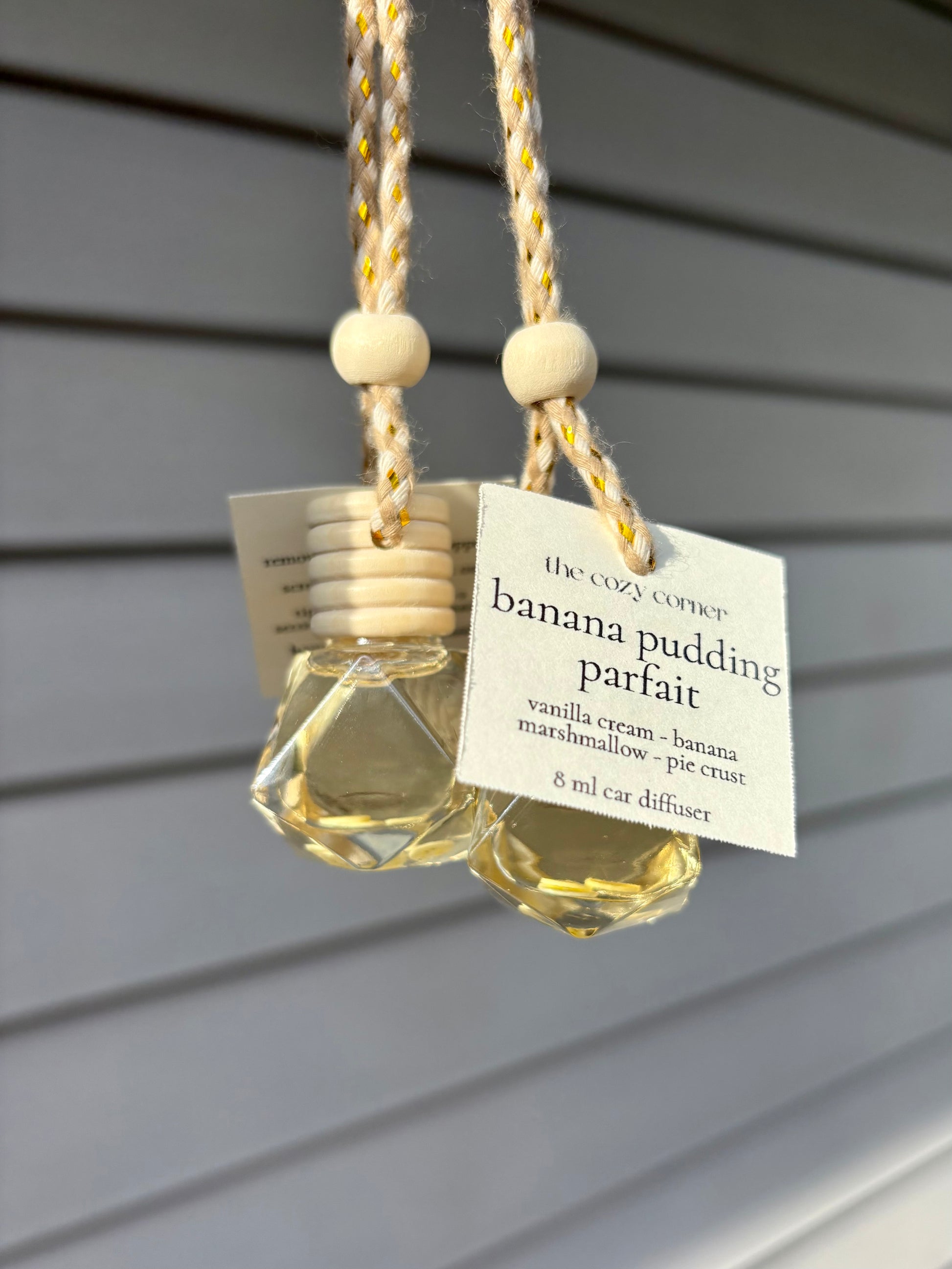 Banana pudding parfait car diffuser hanging against a gray wall