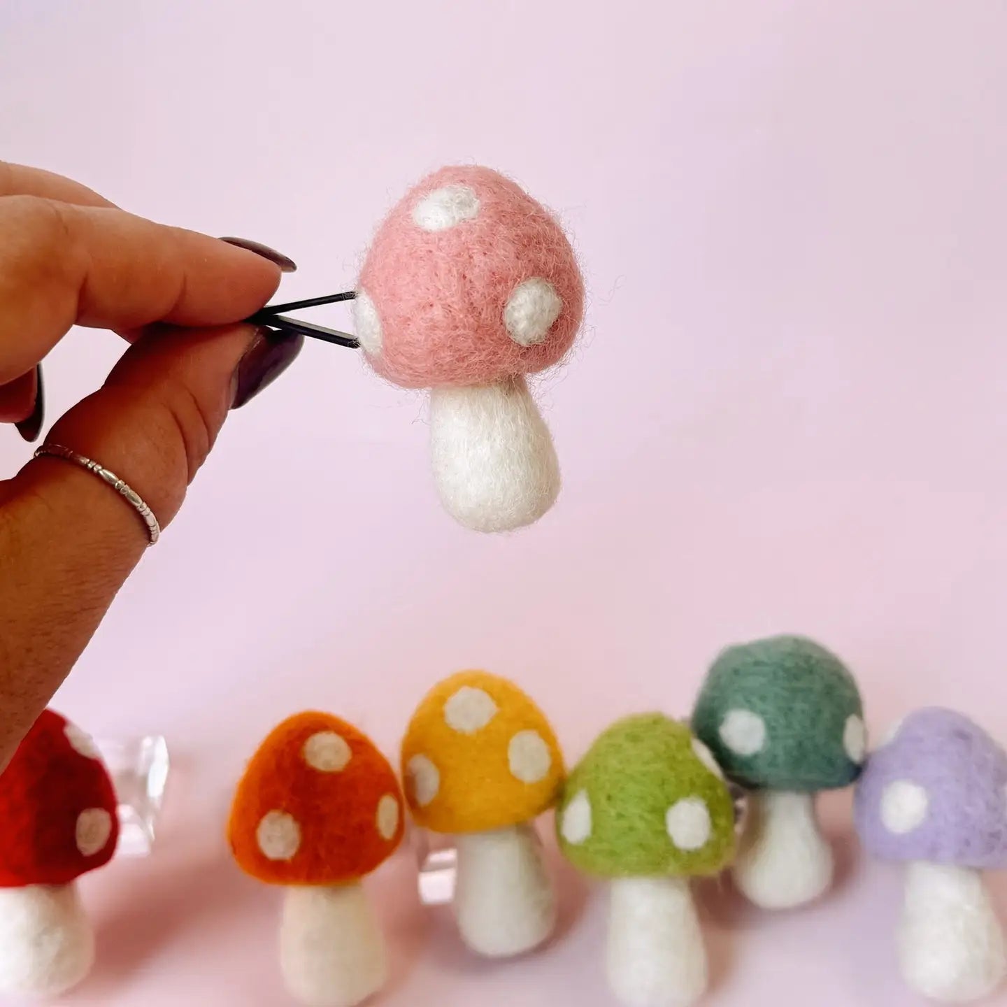 Colorful felt mushroom earrings on a pink background
