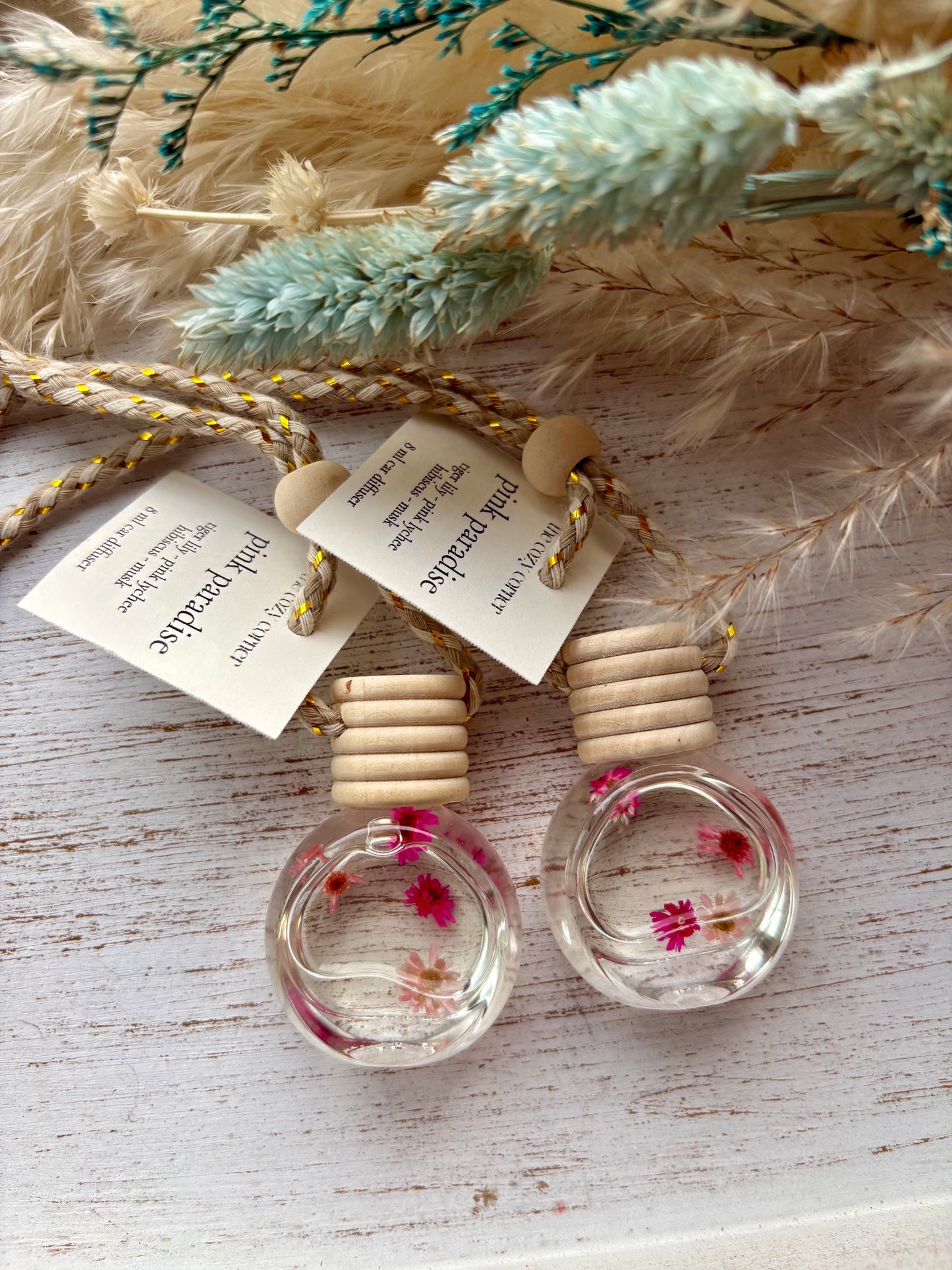 Small glass bottles with wooden tops on a textured surface with dried plants.