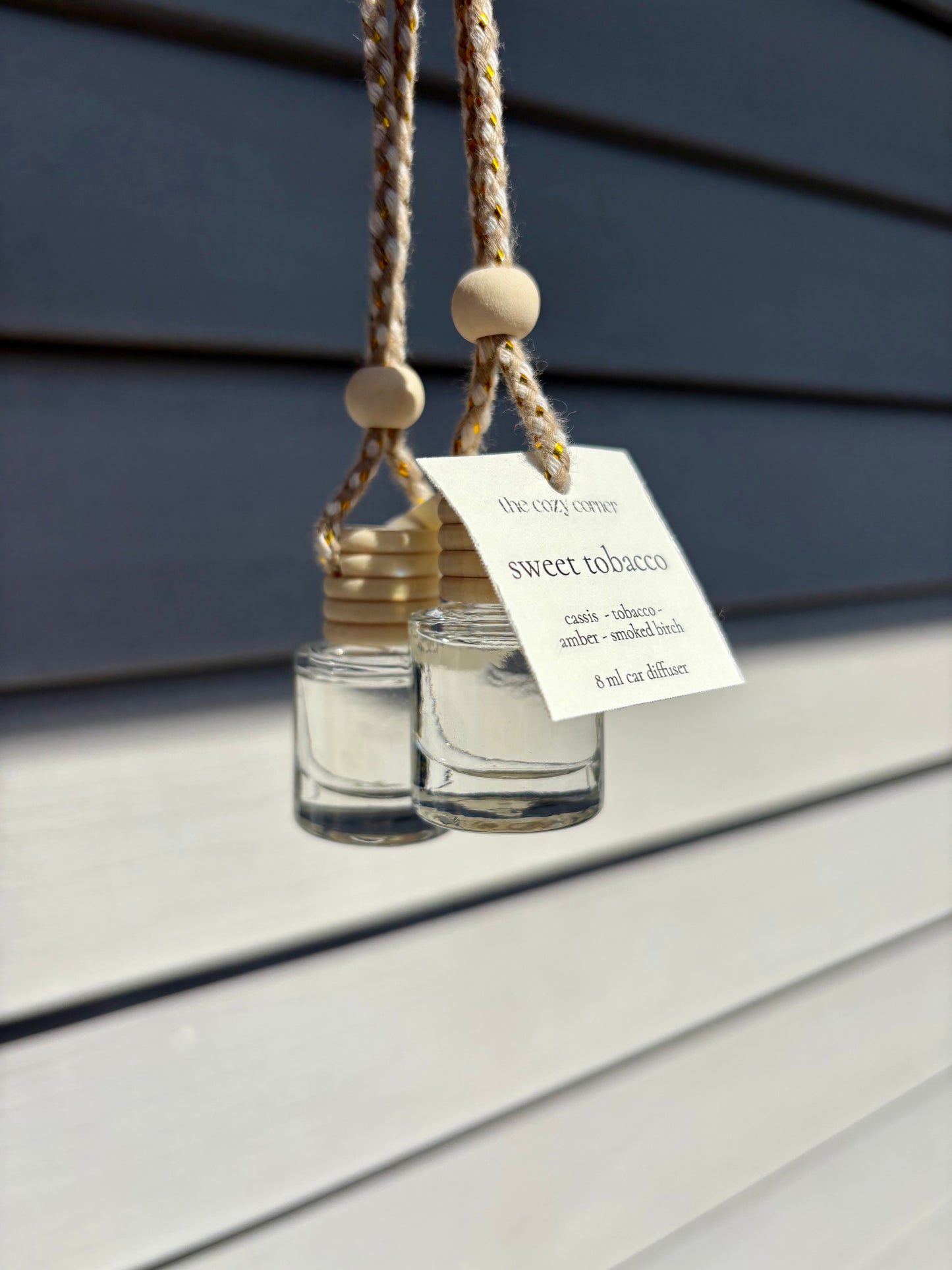 Two hanging glass diffusers with wooden beads on a wooden surface.
