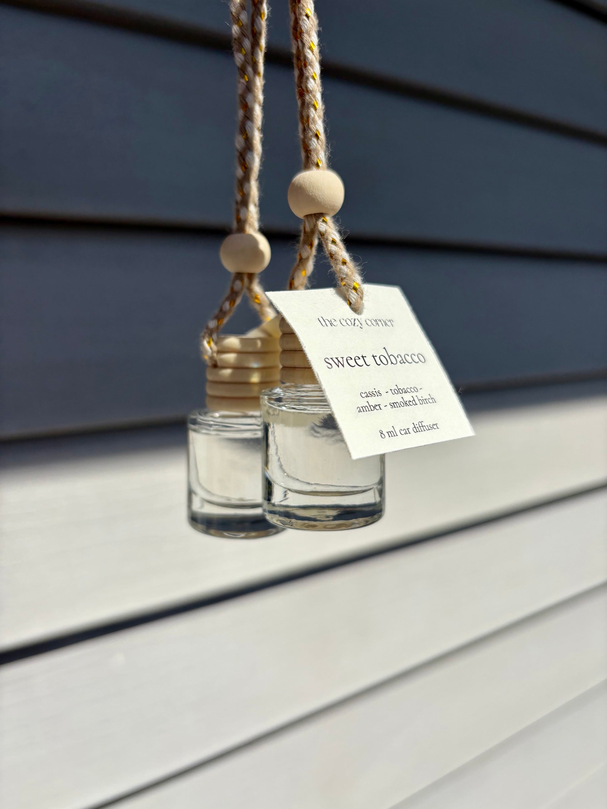 Two hanging glass diffusers with wooden beads on a wooden surface.