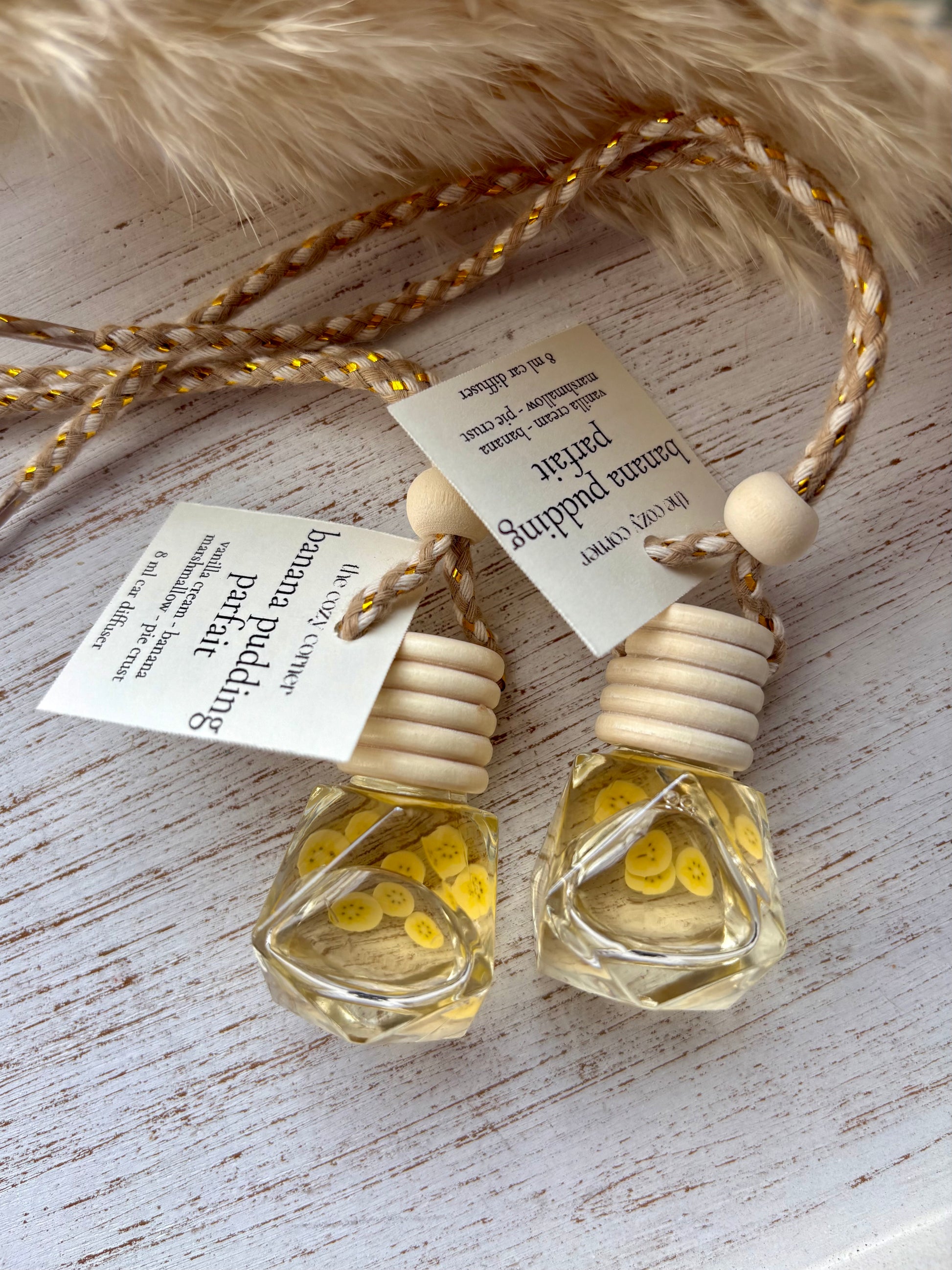 Two small glass bottles with wooden tops on a textured surface with tags.
