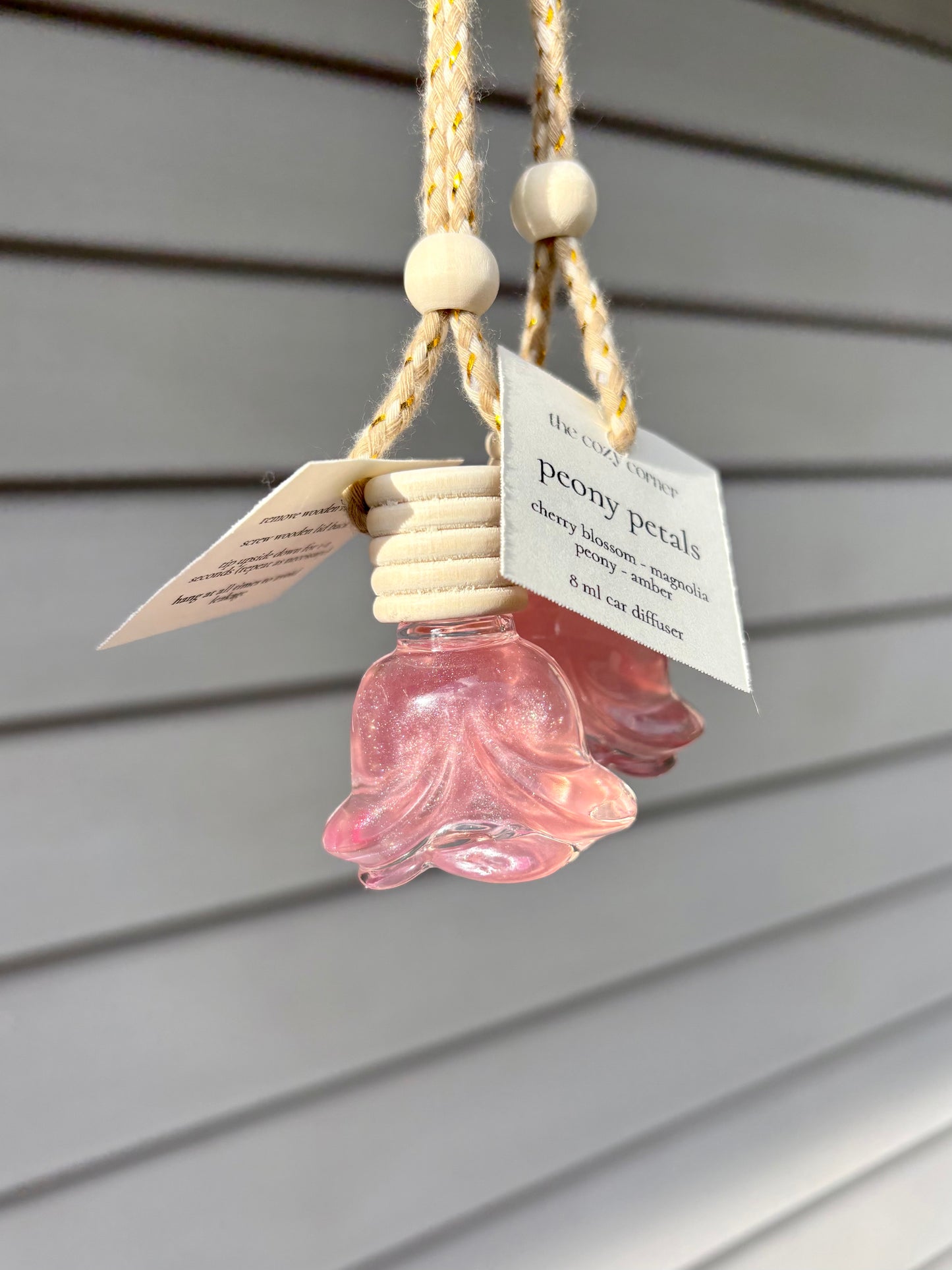 Pink flower-shaped hanging diffuser with a label on a wooden surface