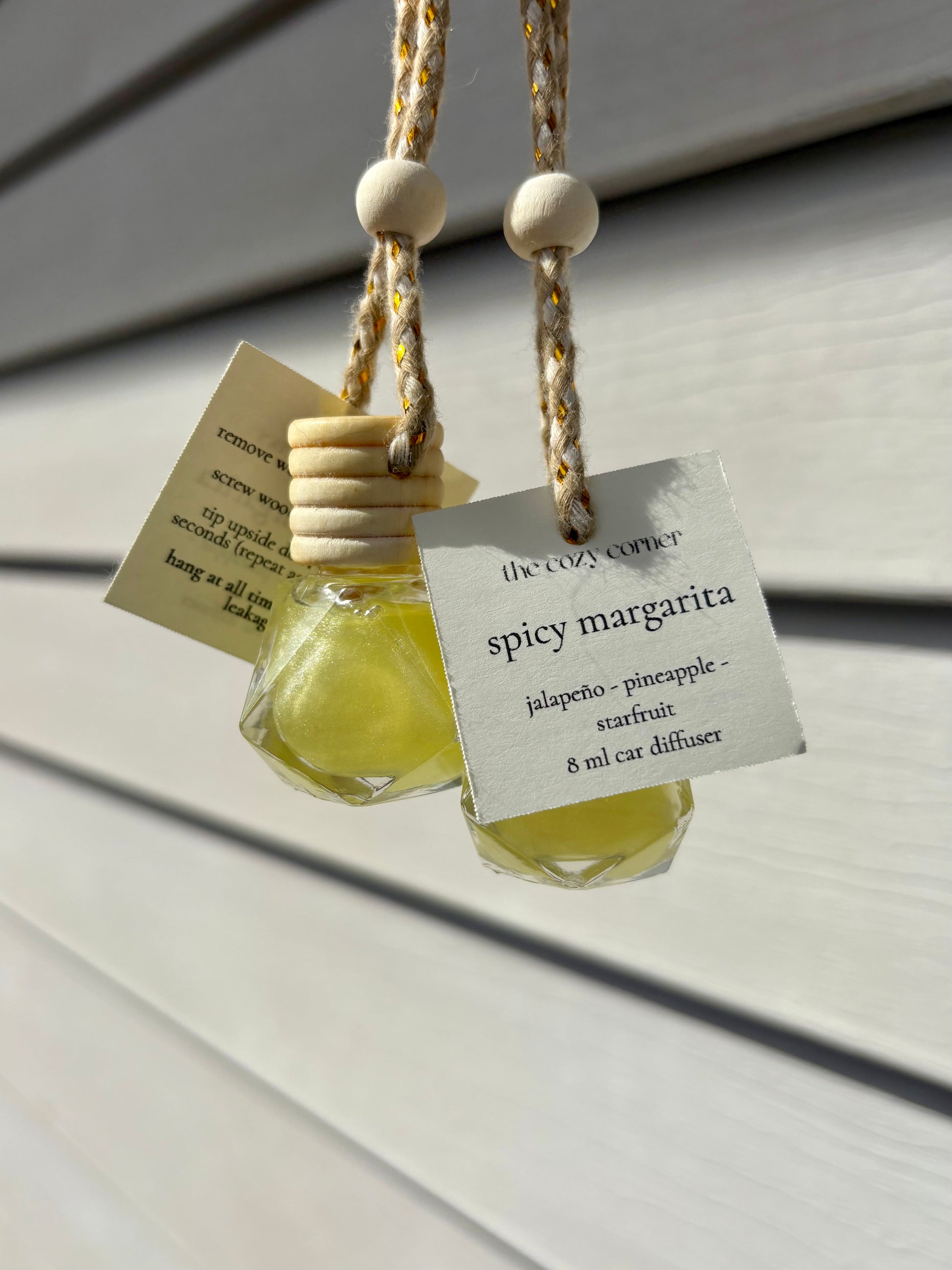 Spicy margarita-scented car diffuser with a label on a light wooden surface