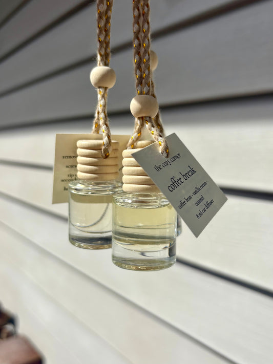Two small glass bottles with wooden stoppers hanging against a neutral background