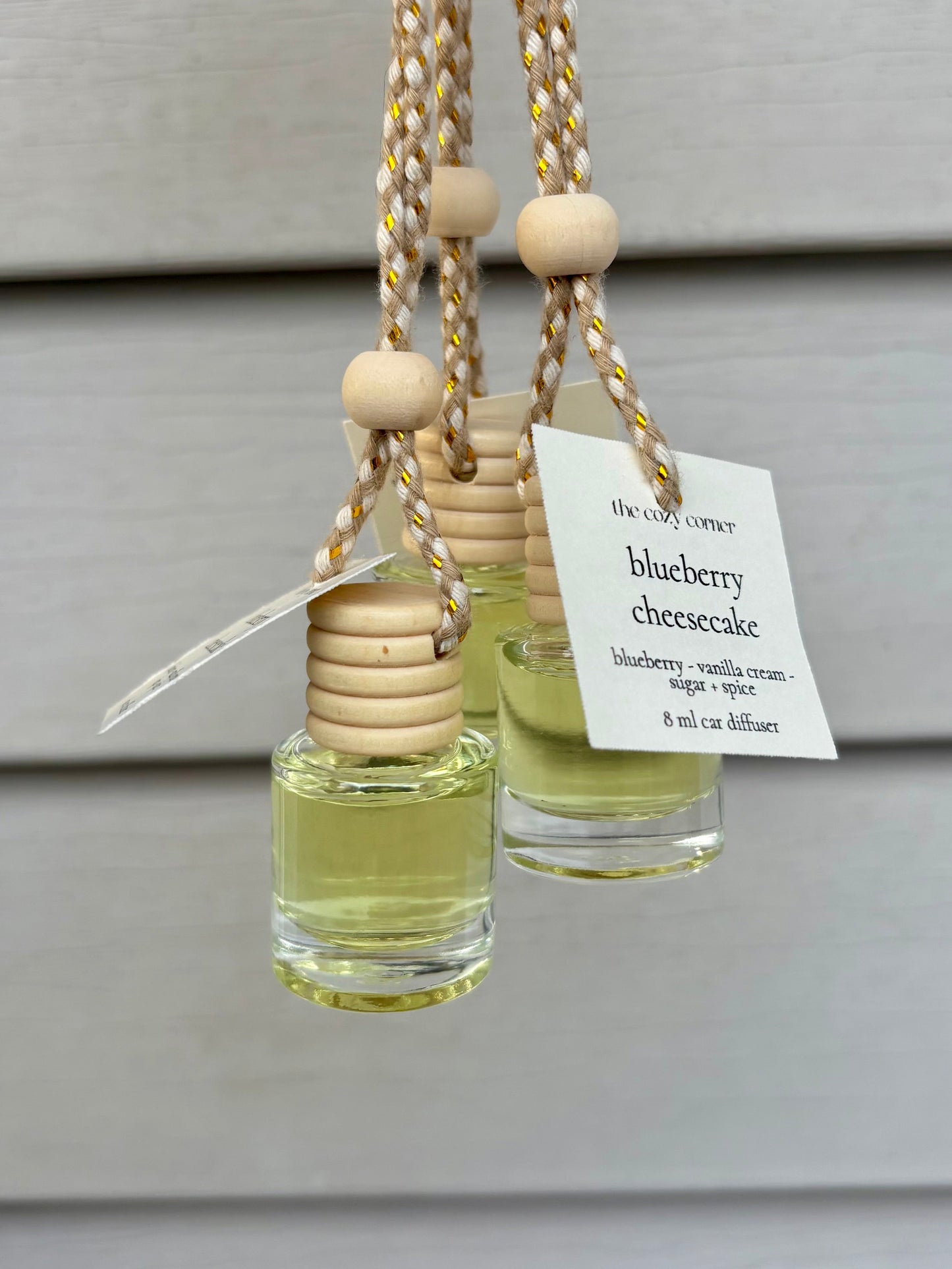 Two small glass diffusers with wooden beads and a 'blueberry cheesecake' label on a neutral background.