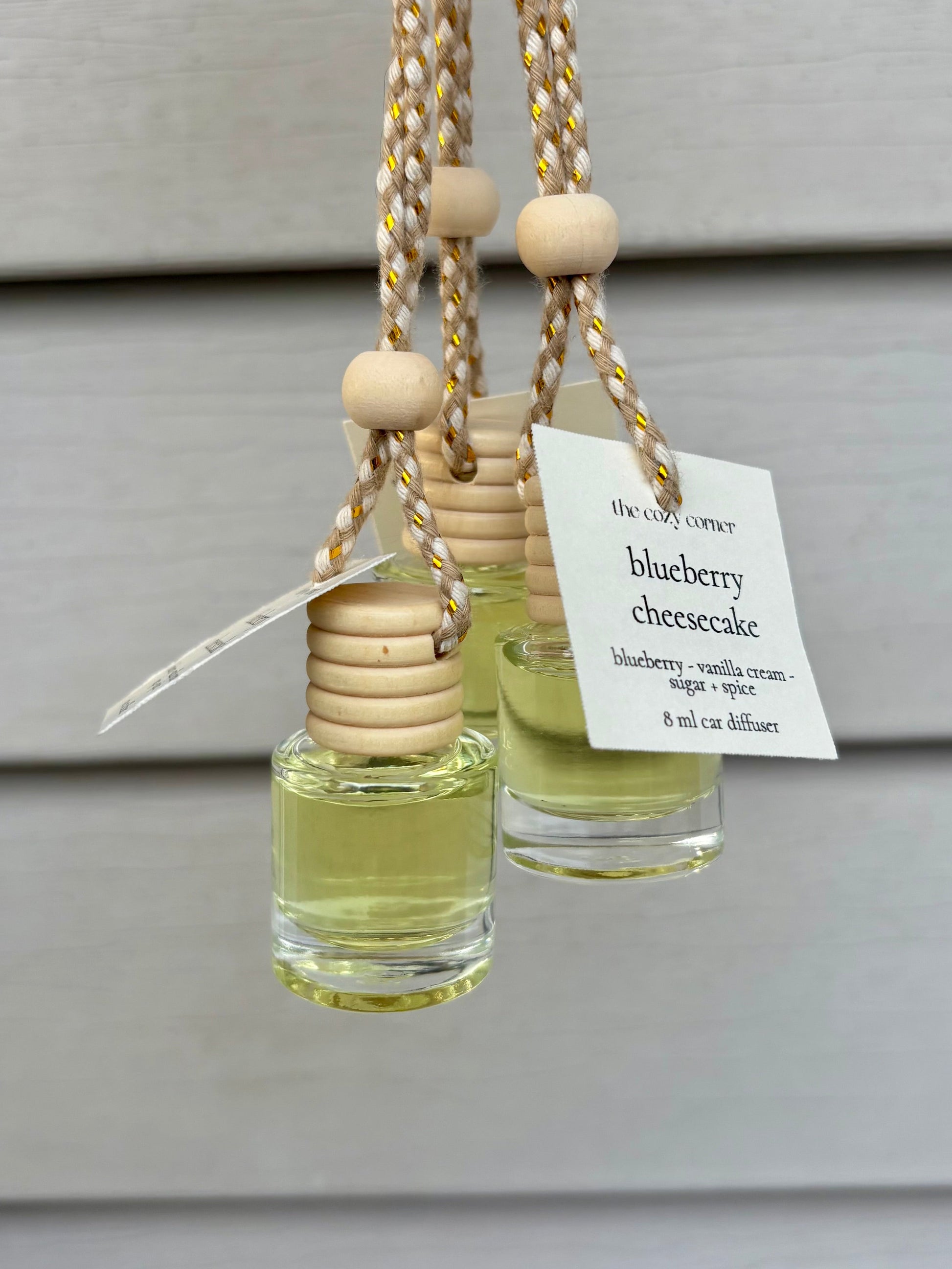 Two small glass diffusers with wooden beads and a 'blueberry cheesecake' label on a neutral background.