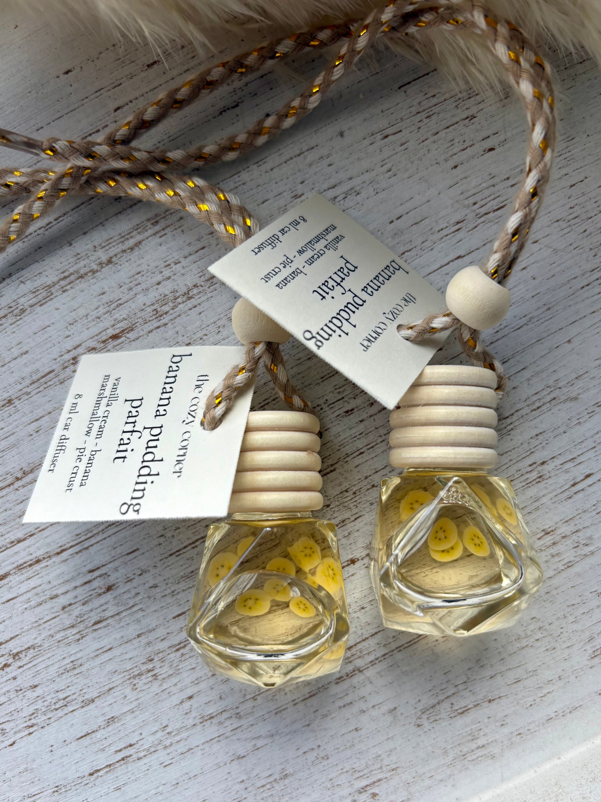 Two small glass bottles with wooden caps on a textured surface with tags.