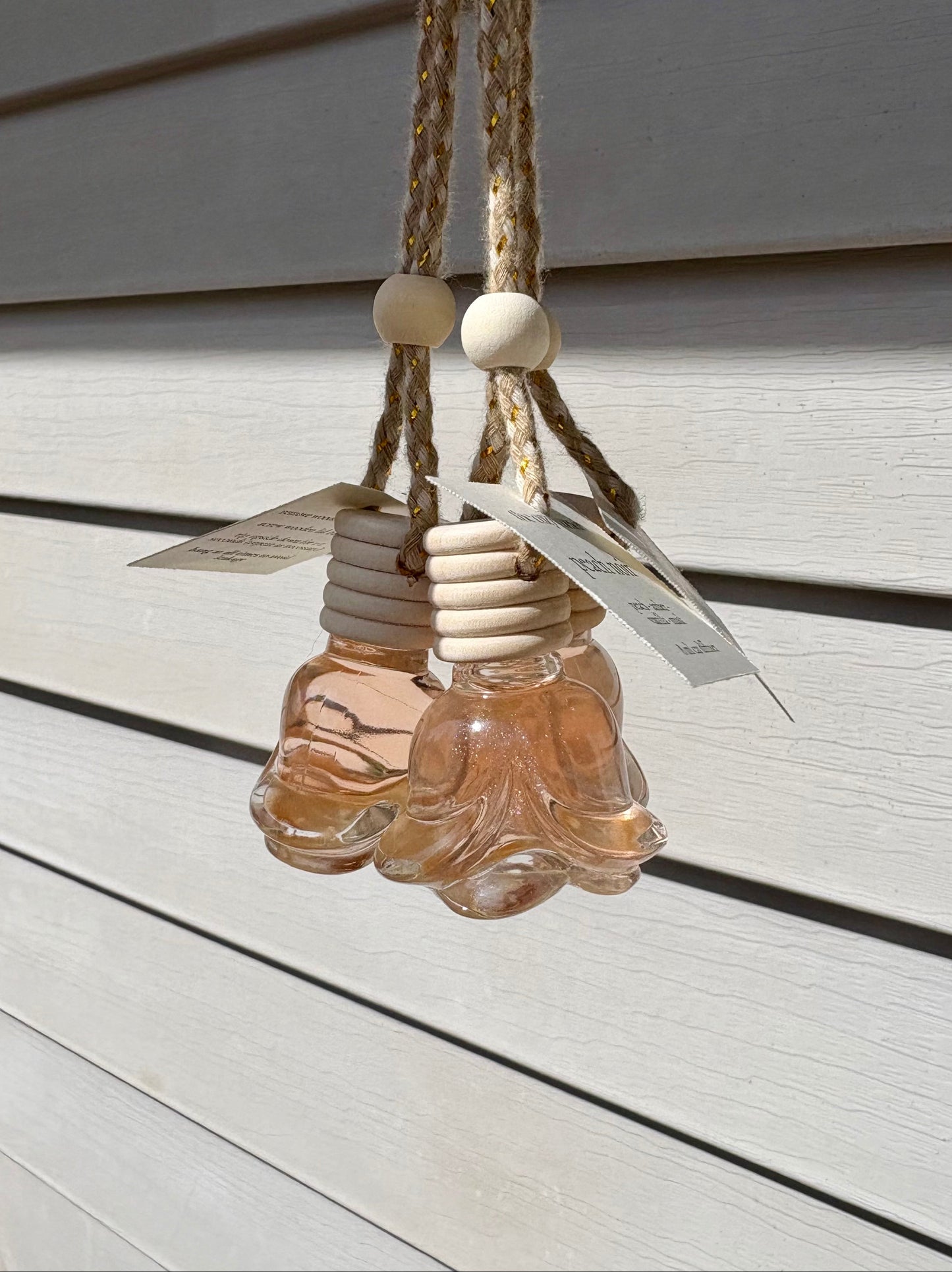 Decorative hanging light fixture with glass bottles and wooden beads on a neutral background