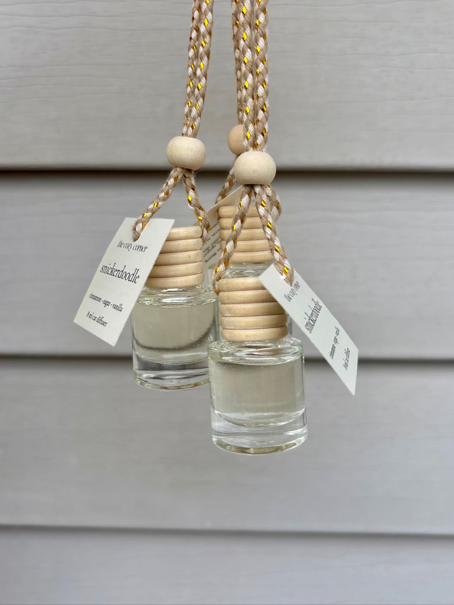 Two small glass bottles with wooden beads and labels on a gray background