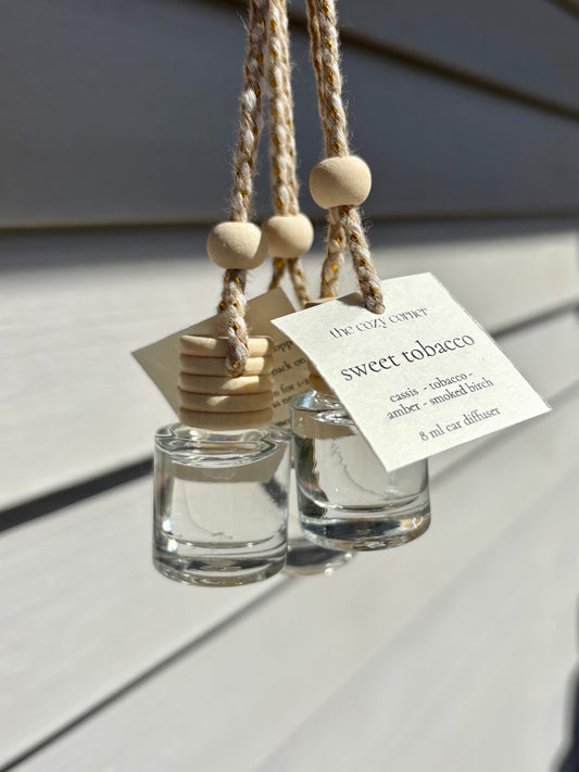 Two small glass diffusers with wooden beads and labels on a light wooden surface.