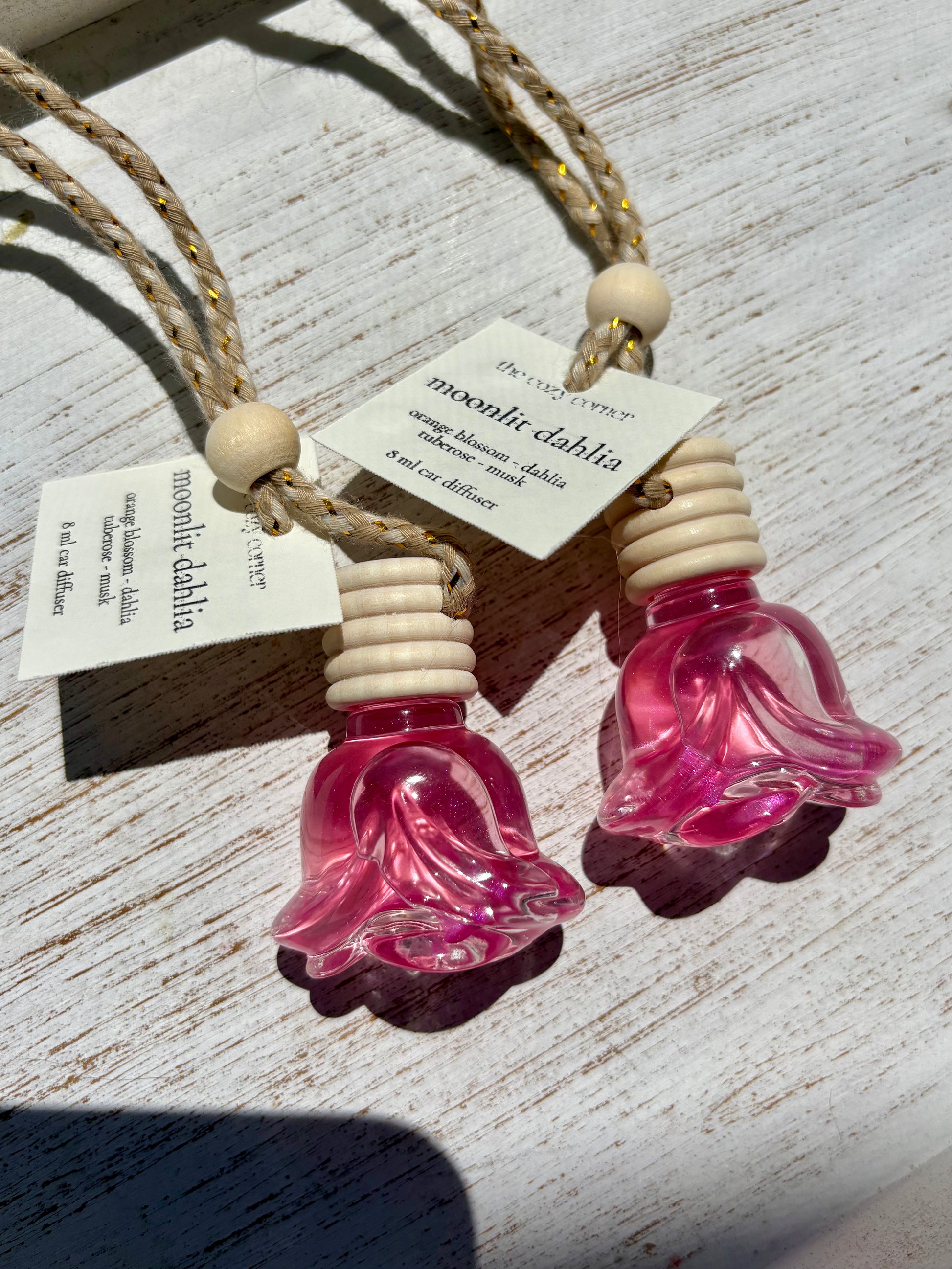Pink glass diffuser with wooden beads on a light wooden surface