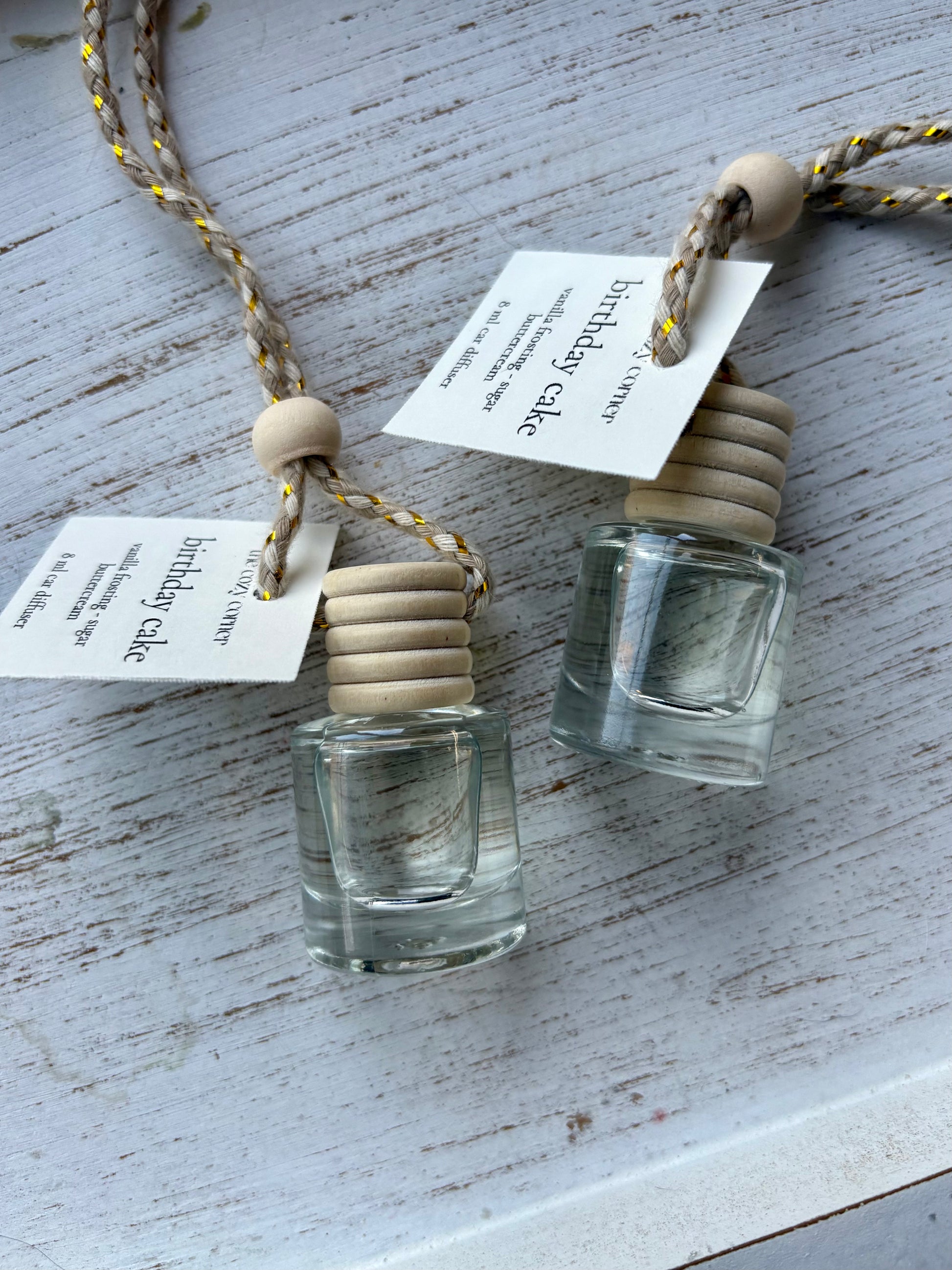 Two small glass bottles with wooden stoppers on a textured surface with tags attached.