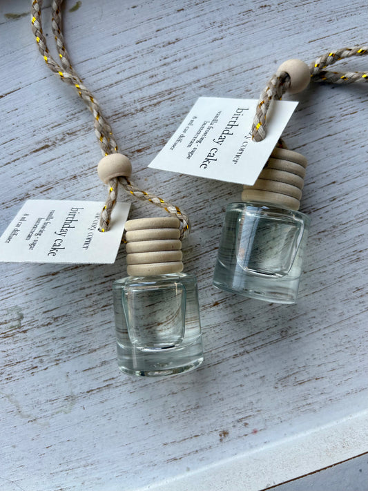 Two small glass bottles with wooden stoppers on a textured surface with tags attached.