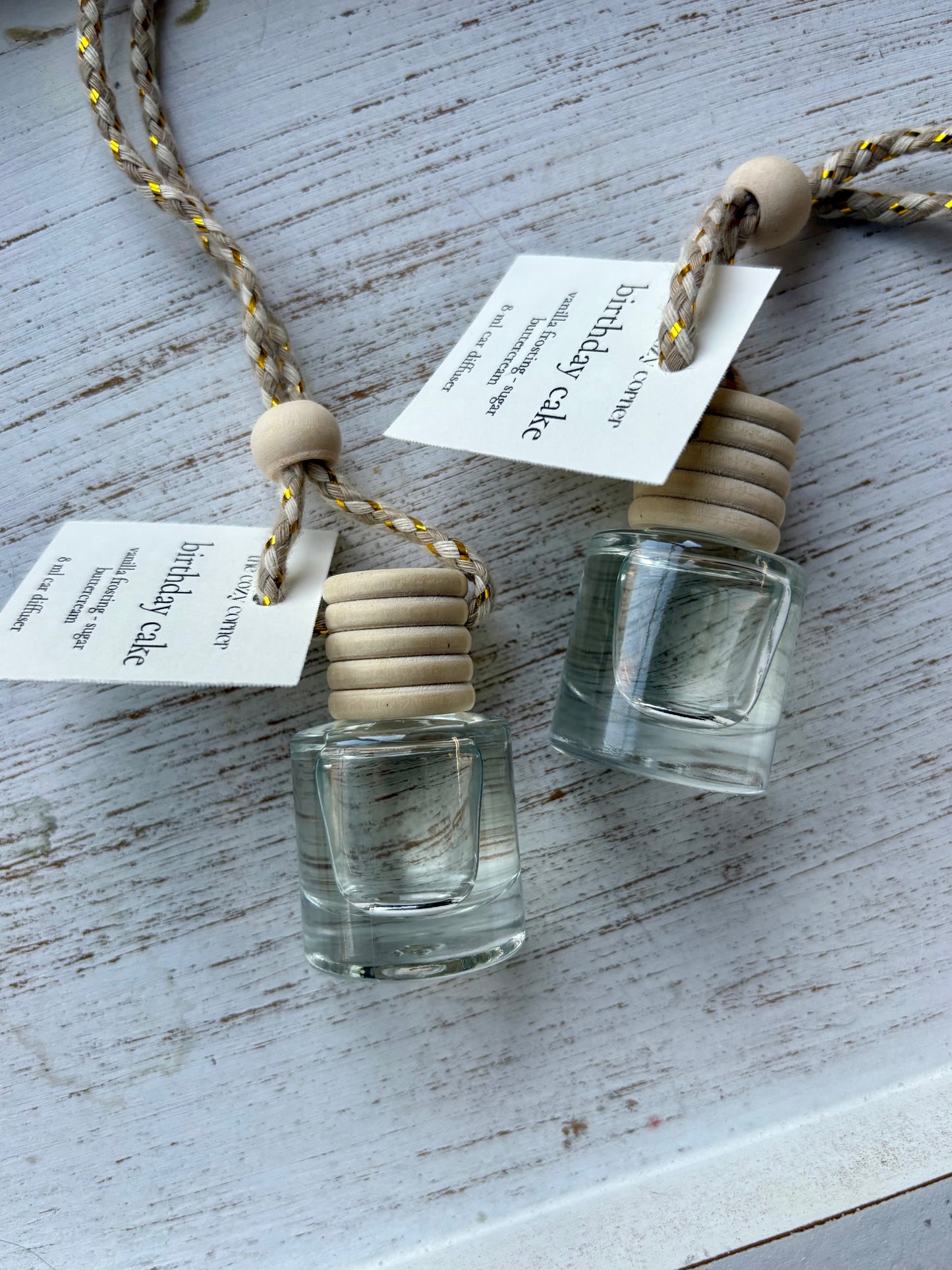 Two small glass bottles with wooden stoppers on a textured surface