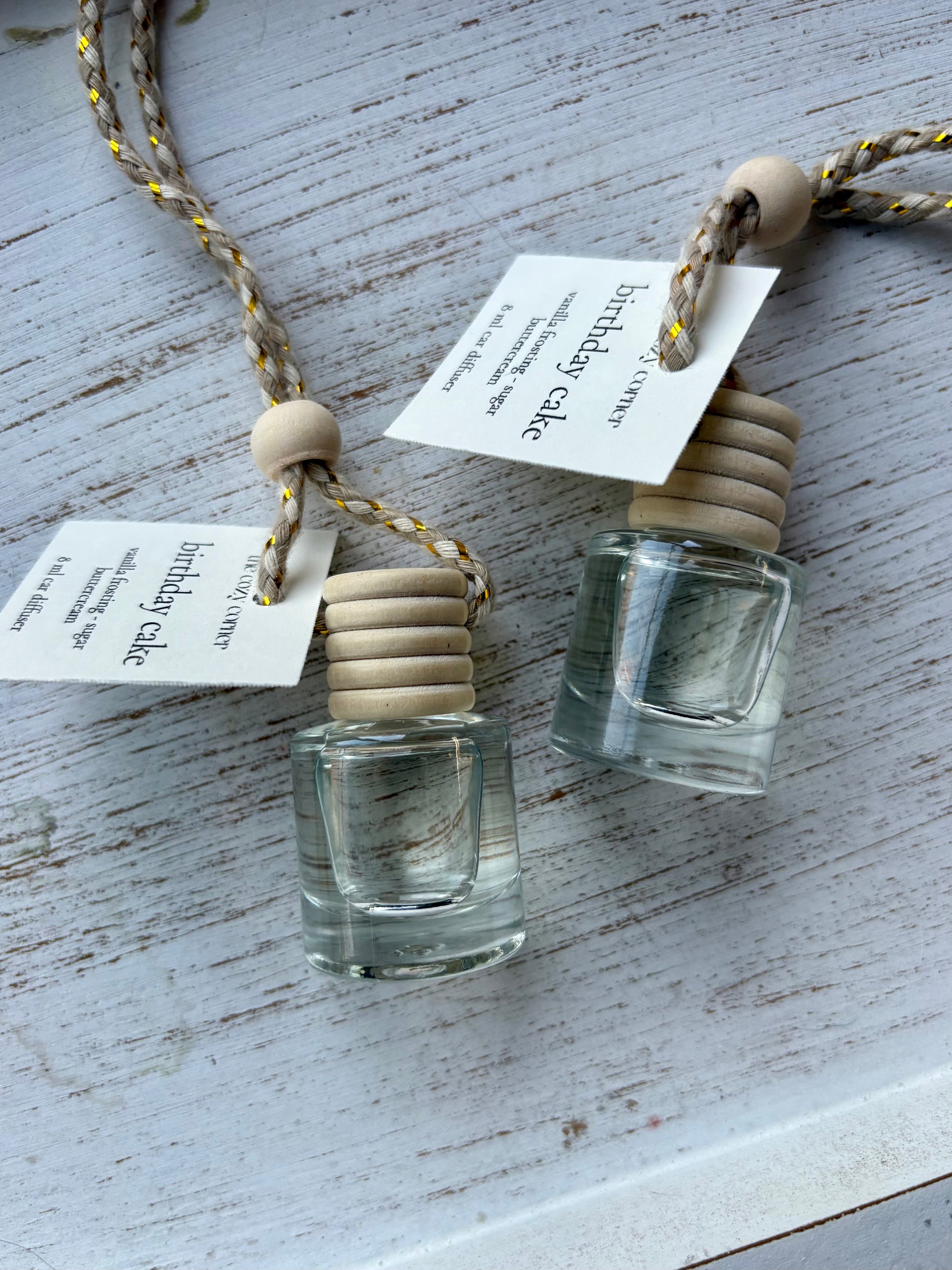Two small glass bottles with wooden stoppers on a textured surface